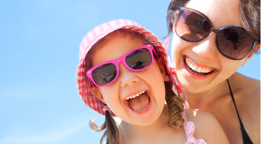 happy mother and daughter on beach with sunglasses